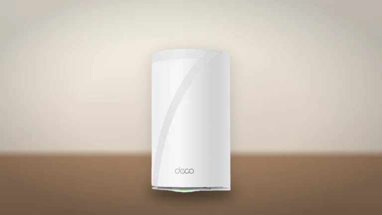 A white cylindrical Deco BE65 Pro node seen from the side, with a curved line of grooves and the deco logo, on a wooden shelf